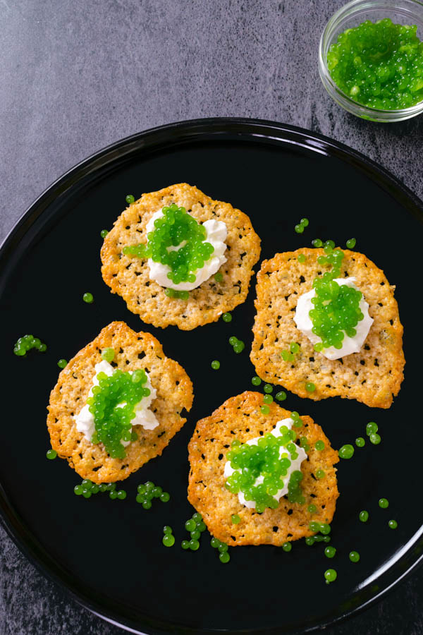 Antipasto di sfoglie di parmigiano con panna acida e caviale molecolare immagine