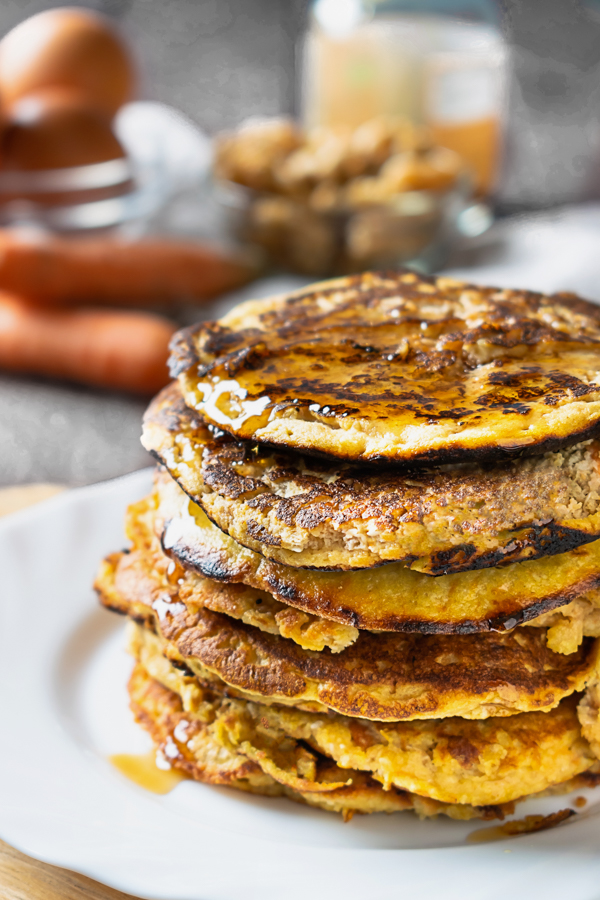 Pila di pancake chetogenici alle carote decorati con sciroppo d'acero senza zucchero.