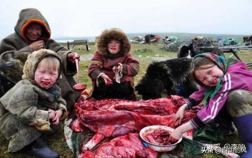 Bambini eschimesi che mangiano carne cruda con le mani